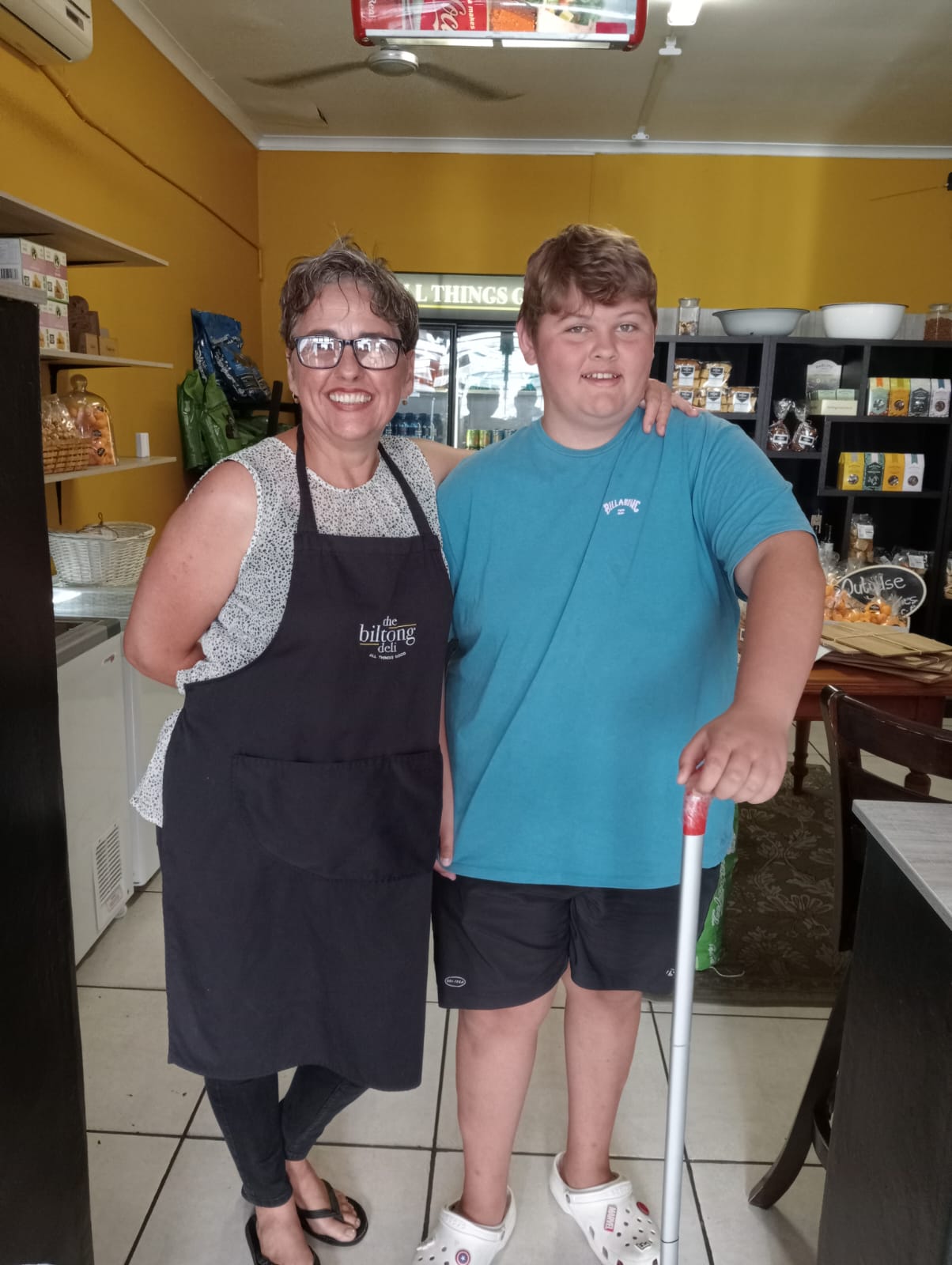 Owner standing with a young customer in front of shelves
